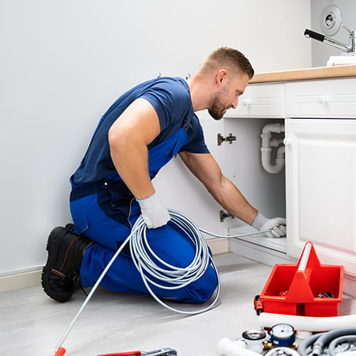 Pracownik pogotowia kanalizacyjnego udrażnia zatkany zlew